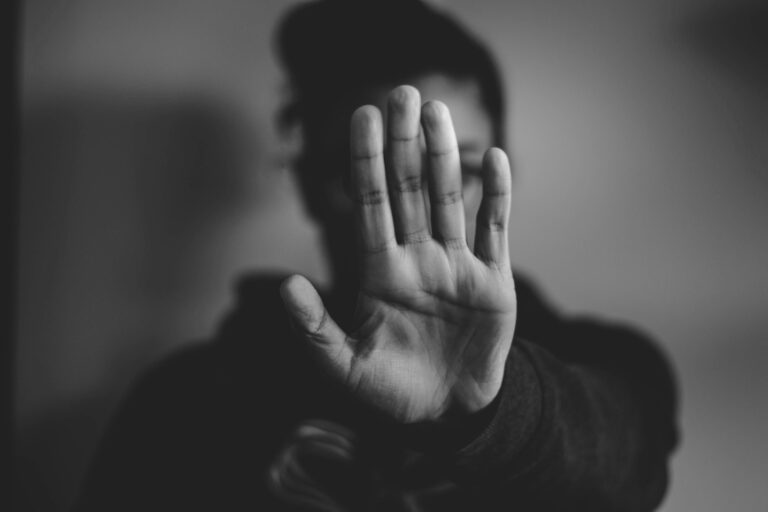 Eine Frau streckt abwehrend die Hand aus. Damit zeigt sie, dass sie das Erbe ausschlagen und ihr Vermögen schützen will.