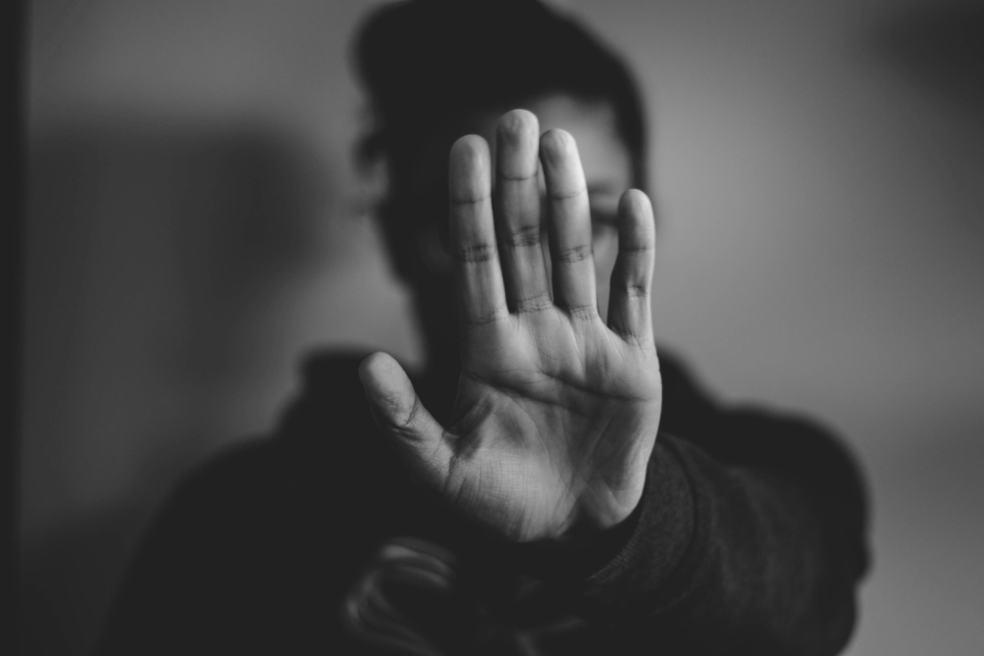 Eine Frau streckt abwehrend die Hand aus. Damit zeigt sie, dass sie das Erbe ausschlagen und ihr Vermögen schützen will.